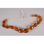 A STRAND OF FACETED & GRADUATED AMBER BEADS, fifteen beads total 14cms long