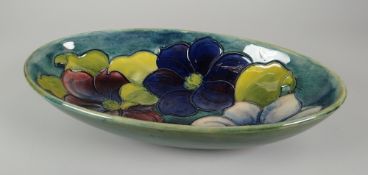 A MOORCROFT POTTERY OVAL DISH in the 'Clematis' pattern with tube-lined flowers to a green ground,