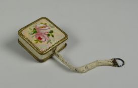 A GUILLOCHE ENAMEL-TYPE DRESS-MAKER'S TAPE-MEASURE with pretty rose decoration to the top and return
