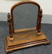 A VICTORIAN MAHOGANY TOILET MIRROR with arched glass frame swivelling on fluted & carved supports