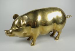 A BRASS MONEY BOX in the form of a standing pig, with loop tail and coin slot, 27cms high