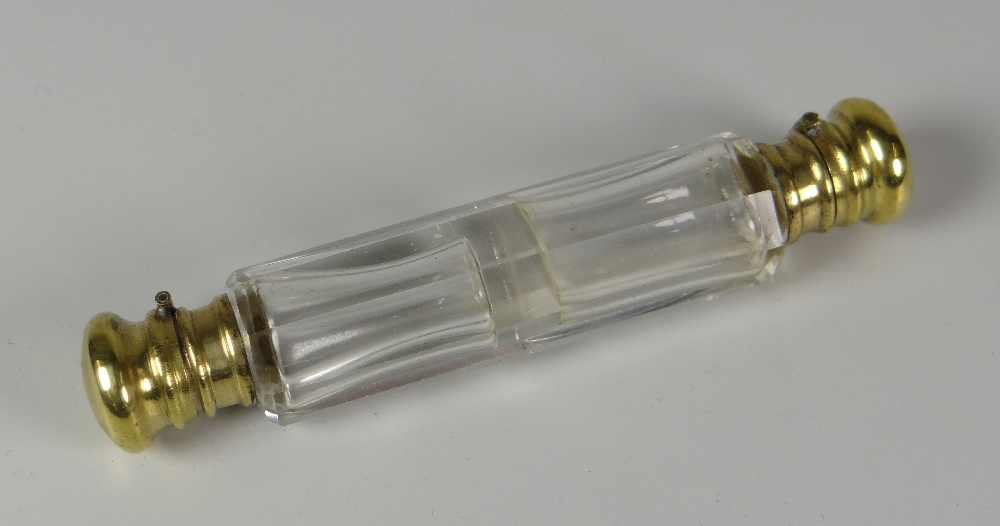 A VICTORIAN FACETED CLEAR GLASS DOUBLE-END SCENT BOTTLE with hinging yellow metal lids and collars,