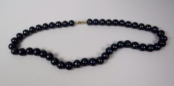 A STRAND OF BLACK PEARLS with 9ct hallmarked gold clasp, 42cms long