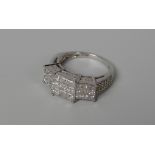 A DIAMOND CLUSTER RING of stepped form and with diamonds to the shoulders in 9ct white gold, 2.5-3ct