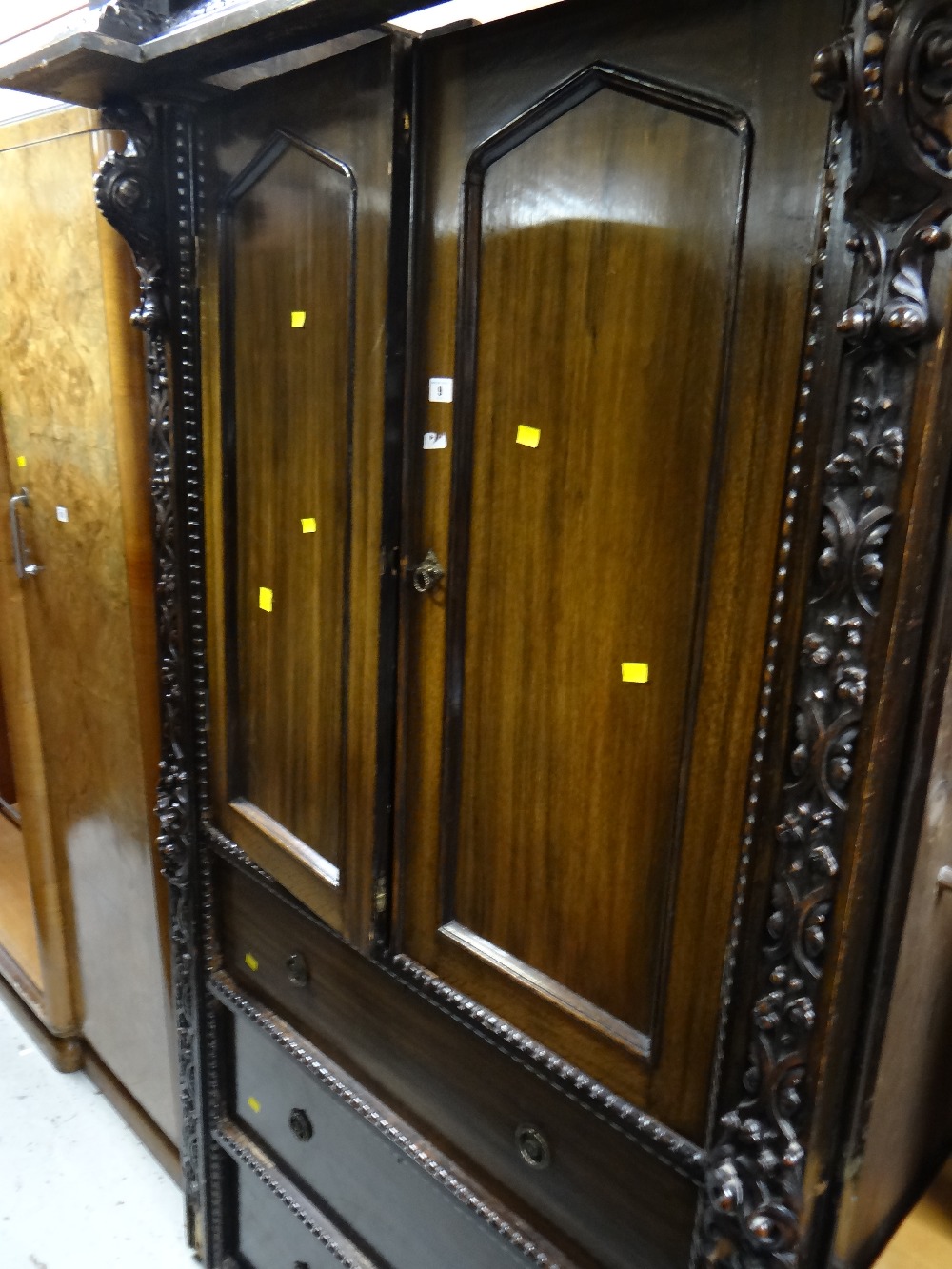 An early twentieth century oak press cupboard with three drawers & profuse carving to the side