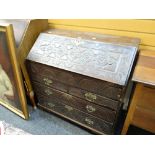 An antique oak drop down bureau with profuse carving & brass fittings