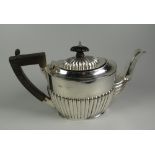 A BACHELOR SIZE SILVER TEAPOT having a composite handle and knop and having a fluted body, hallmarks