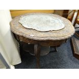 A profusely carved shaped-top Indian-style occasional table with a pierced metal decorated