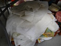 A crate of various table linen, net curtains etc