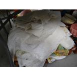 A crate of various table linen, net curtains etc