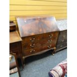 A vintage flame mahogany three-door drop down bureau on raised feet