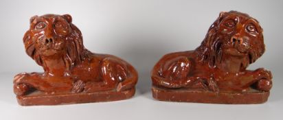 A PAIR OF RARE OBLONG BASED GLAZED TERRACOTTA PIL RECLINING LIONS, 23cms long (believed to be by