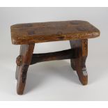 A SMALL WELSH STAINED PINE STOOL with joined stretcher and seat, 22cms high