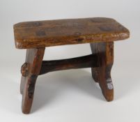 A SMALL WELSH STAINED PINE STOOL with joined stretcher and seat, 22cms high
