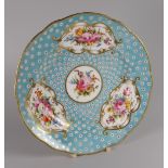 A NANTGARW PLATE of lobed form decorated with four panels of colourful flower sprays within gilded