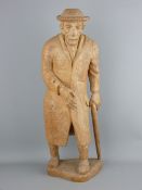 A POSSIBLY CONTINENTAL CARVED WOOD FIGURINE of an elderly gentleman in a hat and overcoat with
