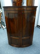 A BOW FRONT GEORGIAN MAHOGANY WALL HANGING CORNER CUPBOARD, 107.5 cms high, 77 cms wide