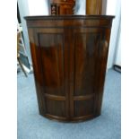 A BOW FRONT GEORGIAN MAHOGANY WALL HANGING CORNER CUPBOARD, 107.5 cms high, 77 cms wide