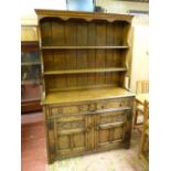 A QUALITY REPRODUCTION OAK DRESSER with blind carved detail to the doors, 185 cms high, 122 cms