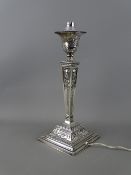 A SILVER CANDLESTICK with classical swag decoration, tapering column and stepped square base,