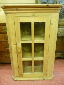 A SINGLE DOOR STRIPPED PINE HANGING CORNER CUPBOARD with six glazed panels, 97 cms high, 62 cms
