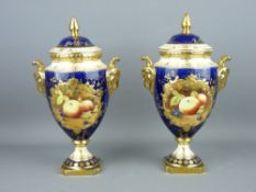 A PAIR OF COALPORT FRUIT DECORATED URN SHAPED VASES & COVERS, cobalt ground with gilt decoration and