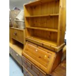 A honey pine sloped top bureau together with a narrow pine small bookcase