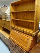 A honey pine sloped top bureau together with a narrow pine small bookcase