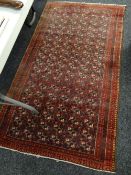 A mainly red ground Middle Eastern multi-squared pattern with narrow border, 176 x 97cms
