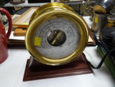 Modern brass barometer mounted on a wooden plinth