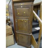 An antique oak two-door standing corner cupboard