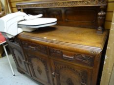 A vintage carved oak railback sideboard with three drawers above three cupboards, 133 x 153 x 53cms