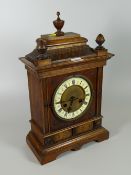 A decorative carved & inlaid oak mantel clock with enamel dial & Roman numerals
