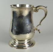 A GEORGE III SILVER TANKARD bell-shaped with spreading circular foot, scrolling feathered handle,