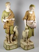 A PAIR OF ROYAL DUX SHEPHERDS standing in peasant robes and with goat and sheep at respective