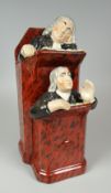 A STAFFORDSHIRE EARTHENWARE GROUP OF VICAR & MOSES seated in two conjoining pulpits with mottle