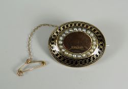 A VICTORIAN MOURNING BROOCH of oval form in enamelled 9ct yellow gold, set with seed-pearls, in