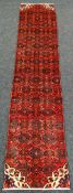 A LARGE PERSIAN HANADAN RUNNER red ground all-over design, 74 x 347cms