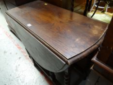 A dark oak drop leaf gate-leg table with barley-twist legs