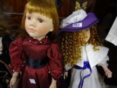 Doll with red dress and long black skirt and doll with cream dress, purple bonnet and with full