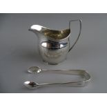 A GEORGE III SILVER CREAM JUG and a pair of later sugar tongs, London 1802 and 1926 respectively,