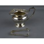 A SMALL CLASSICALLY STYLED SILVER CREAM JUG and a pair of sugar tongs, Chester 1890 and Birmingham