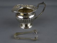A SMALL CLASSICALLY STYLED SILVER CREAM JUG and a pair of sugar tongs, Chester 1890 and Birmingham