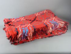 A RED WELSH WOOLLEN BLANKET in traditional multi-coloured design with tasselled edges, 240 x 210 cms