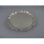 A CIRCULAR SILVER CARD TRAY WITH WAVY BORDER on four hoof feet, Sheffield 1961, 5 troy ozs, 15.5 cms