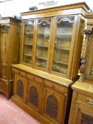 A CIRCA 1900 OAK THREE DOOR BOOKCASE with floral carved detail and interior adjustable shelves,