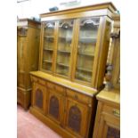 A CIRCA 1900 OAK THREE DOOR BOOKCASE with floral carved detail and interior adjustable shelves,