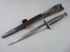 A FAIRBAIRN SYKES COMMANDO FIGHTING KNIFE IN SCABBARD, the upper grip stamped with the number