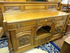 A GOOD CARVED OAK RAILBACK SIDEBOARD with dog kennel centre and stylized brasswork, 123 cms high
