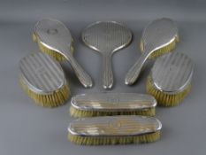 A FIVE PIECE SILVER DRESSING TABLE HAND MIRROR & BRUSH SET, Birmingham 1918 and two similarly styled